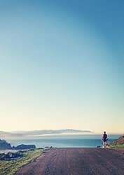 Bicyclist looking out over hill at ocean